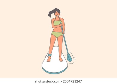 Woman surfer uses SUP board to float down river, and rows paddle to adjust direction, dressed in swimsuit. Happy girl relaxing at sea on vacation and getting into SUP surfing at sunny resort