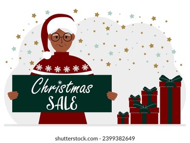 A woman in a sweater and a red Santa hat holds a poster with the text about Christmas sale in his hand.