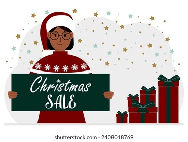 A woman in a sweater and a red Santa hat holds a poster with the text about Christmas sale in his hand.