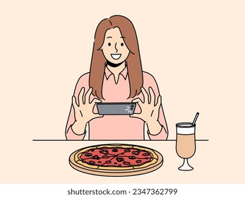 Woman takes picture of pizza on phone, wanting to make post on social network and talk about life. Girl blogger take shot of pizza while visiting restaurant of traditional italian cuisine