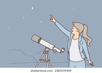 Woman with telescope points finger at starry sky, being fond of astronomy and watching movement of planets in space. Girl stands in open air near telescope on tripod and looks at night sky