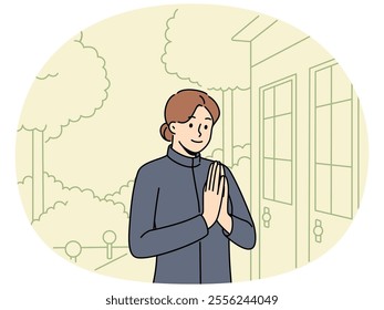 Woman in thai national clothes says hello standing at entrance to asian temple. Girl is fan of thai culture travels through asia and poses near door of building, enjoying architecture of Thailand.