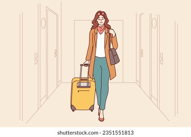 Woman tourist is in corridor of hotel, goes with travel suitcase, after completing business trip. Successful girl with luggage checks into hotel to have good time during summer vacation