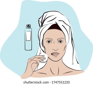 Woman with a towel on her head and in a bathrobe, takes off her makeup