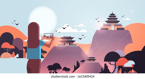 woman traveler photographing chinese pagoda in traditional style on smartphone camera traveling blogging concept rear view tourist sightseeing pavilions architecture landscape of china horizontal