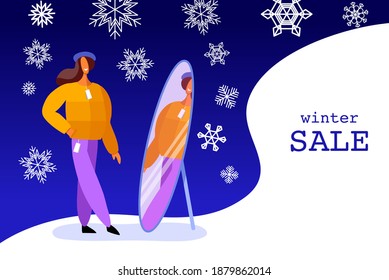 Woman tries on clothes. Winter shopping. A girl looks in the mirror. Winter background for sale