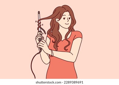 Woman uses electric curling iron to get curly hairstyle and get ready for party or date with boyfriend. Girl with curling iron wants to become beautiful giving straight hair curly look 