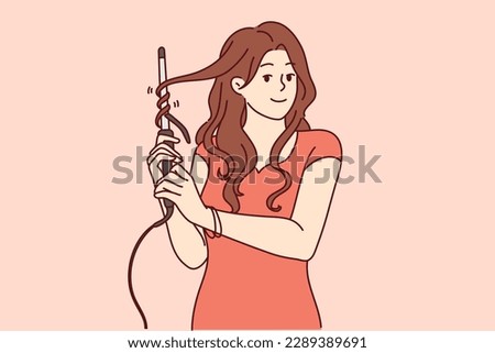 Woman uses electric curling iron to get curly hairstyle and get ready for party or date with boyfriend. Girl with curling iron wants to become beautiful giving straight hair curly look 