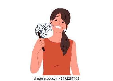 Woman uses electric fan to stop sweating and prevent exhaustion in hot summer weather. Small electric fan inside girl suffering from warming temperatures and lack of air conditioning