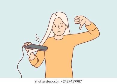 Woman using hair straightener shows thumbs down giving negative feedback about hairstyle care device. Blonde girl is dissatisfied after testing hair straightener that damages curls.