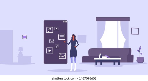 woman using touchscreen smartphone with application icons mobile apps user interface concept modern living room interior horizontal full length