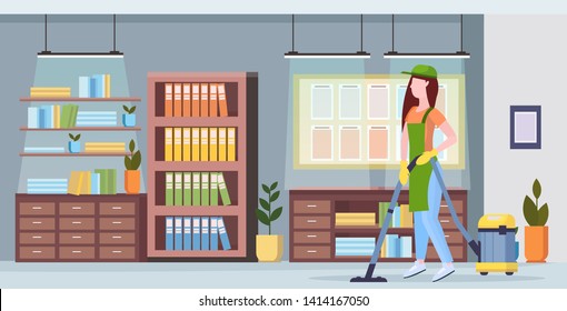 Woman using vacuum cleaner girl in uniform vacuuming.  Floor cleaning service concept.  Modern co-working center office interior.  Flat full length horizontal.