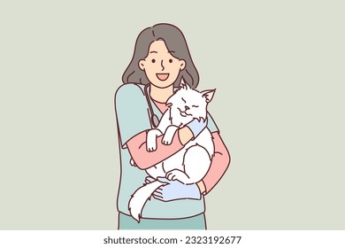Woman veterinarian holds cat belonging to ZOO clinic visitor who brought pet for examination or vaccination. Young girl works as veterinarian and loves to treat animals and take care of kittens.