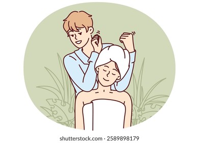 Woman visits massage therapist in SPA salon and sits in towel enjoying relaxing treatments. Man works in SPA center giving shoulder and neck massage to visitor in need of manual procedures