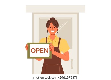 Woman waiter shows inscription open standing near door of restaurant and inviting to become visitor. Hospitable girl waiter or owner of own small business in catering industry, dressed in apron