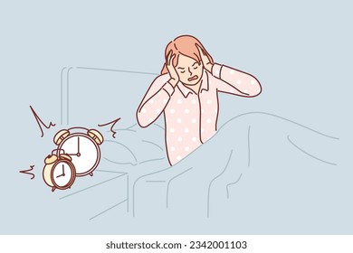 Woman wakes up with difficulty early in morning and closes ears sitting in bed near bedside table with alarm clock. Girl in pajamas wakes up before work and needs extra rest due to overwork