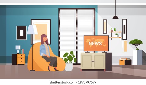 woman watching TV daily news program on television girl sitting on armchair living room interior