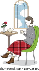 A woman wearing a sweater and drinking tea or coffee