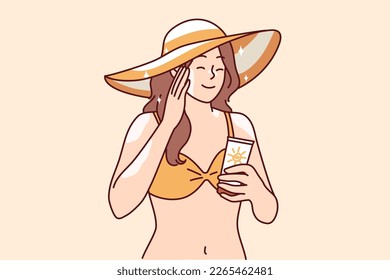 Woman who wants to sunbathe applies sunblock cream to skin to protect herself from sunstroke or to avoid excessive tanning. Girl in bikini and beach hat uses sunblock cream enjoy summer vacation 