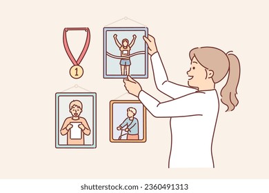 La mujer decorará la pared de un apartamento con fotografías de competencias deportivas y medallas o retratos de un hijo. Chica hace esquina de la gloria en su propia casa, colgando fotos memorables que causan nostalgia