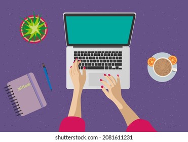 A woman is working behind a computer screen. Top view of the desktop, monitor, keyboard, laptop, notepad, pen, flower, hands, coffee