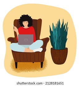 Woman working with laptop in armchair at home