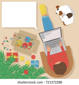 Woman working on laptop at home, sitting in a comfortable chair with a dog near a Christmas tree. On the floor are Christmas balls and gifts. Vector illustration. The view from the top. 