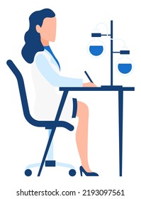 Woman writing scientific report and looking at chemical glass