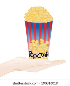 Woman's hand holding object-Full bucket of popcorn isolated on white background.
