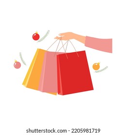 Woman's hand holding paper shopping bags. Christmas holiday time. White background. Vector illustration. Flat style