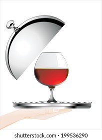 Woman's hand holding silver platter with glass of cognac or brandy  on white background isolated