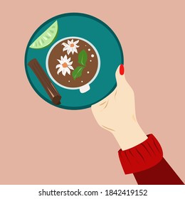A woman's hand holds a Cup of chamomile tea