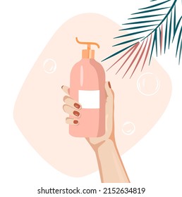 A woman's hand holds a pink bottle with shampoo or shower gel. Cosmetics for hair, body and facial skin care. Beauty product on a pink background with tropical leaves. Spa treatments. Woman