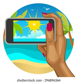 Woman's hand with the smart phone in the background of the beach
