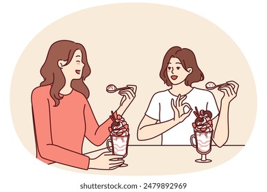 Women having lunch sitting in restaurant eating milkshake and discussing personal lives or plans for weekend. Girlfriends eat ice cream or milkshake in cafe wanting to cool off in hot summer weather