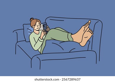 Women lie on sofa with mobile phone in hands and play games or watch videos on social networks. Girl spends free time using phone to relax and enjoy comfort or coziness in apartment.