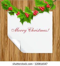 Wood background with sheet of paper and holly berry.