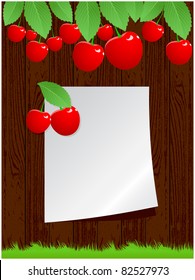 Wooden background with on it a sheet of paper, green grass and berries cherries