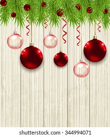 Wooden Christmas background with green fir branches and red baubles