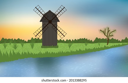 Wooden windmill on the green camp near the blue river.