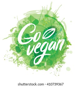 Words GO VEGAN in simple and cute frame with green branches and leaves with watercolor elements in green color.