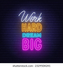 Work Hard Dream Big neon lettering on brick wall background.