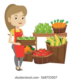 Worker Of Grocery Store Standing In Front Of Section With Vegetables And Fruits. Female Worker Of Grocery Store Holding A Box With Apples. Vector Flat Design Illustration Isolated On White Background.