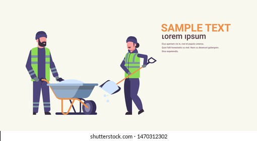 workers couple in uniform using shovel and wheelbarrow winter snow removal concept woman man working together cleaning service flat full length horizontal copy space