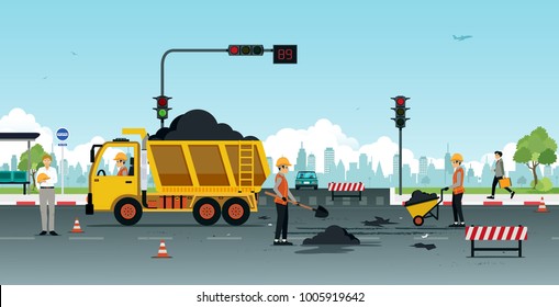 Workers are repairing road surfaces with traffic lights.