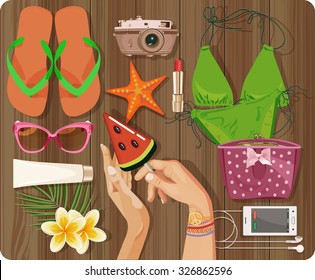 Workplace concept. Top view with textured table, swimsuit, starfish, camera, slippers, cosmetic, phone, headphones, sunglasses, sun cream, candy, lollipop, flowers