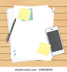 Workplace organization. Top view with wooden table, smartphone, pen, paper, sticky notes and paper clips.