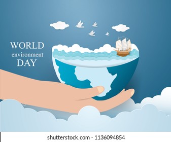 World environment day concept with Barque on the blue sea in the earth on hand,paper craft style