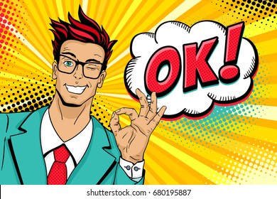 Wow pop art male face. Young handsome man in glasses smiles, winks and shows okay sign and OK! speech bubble. Vector illustration in retro comic style. Vector pop art background. Invitation poster.