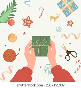 Wrapping christmas gift box. Preparing for Christmas and New Year. Christmas cookies, scissors, ball, spruce branch, Christmas ball, candy, snowflake, stars, tinsel.